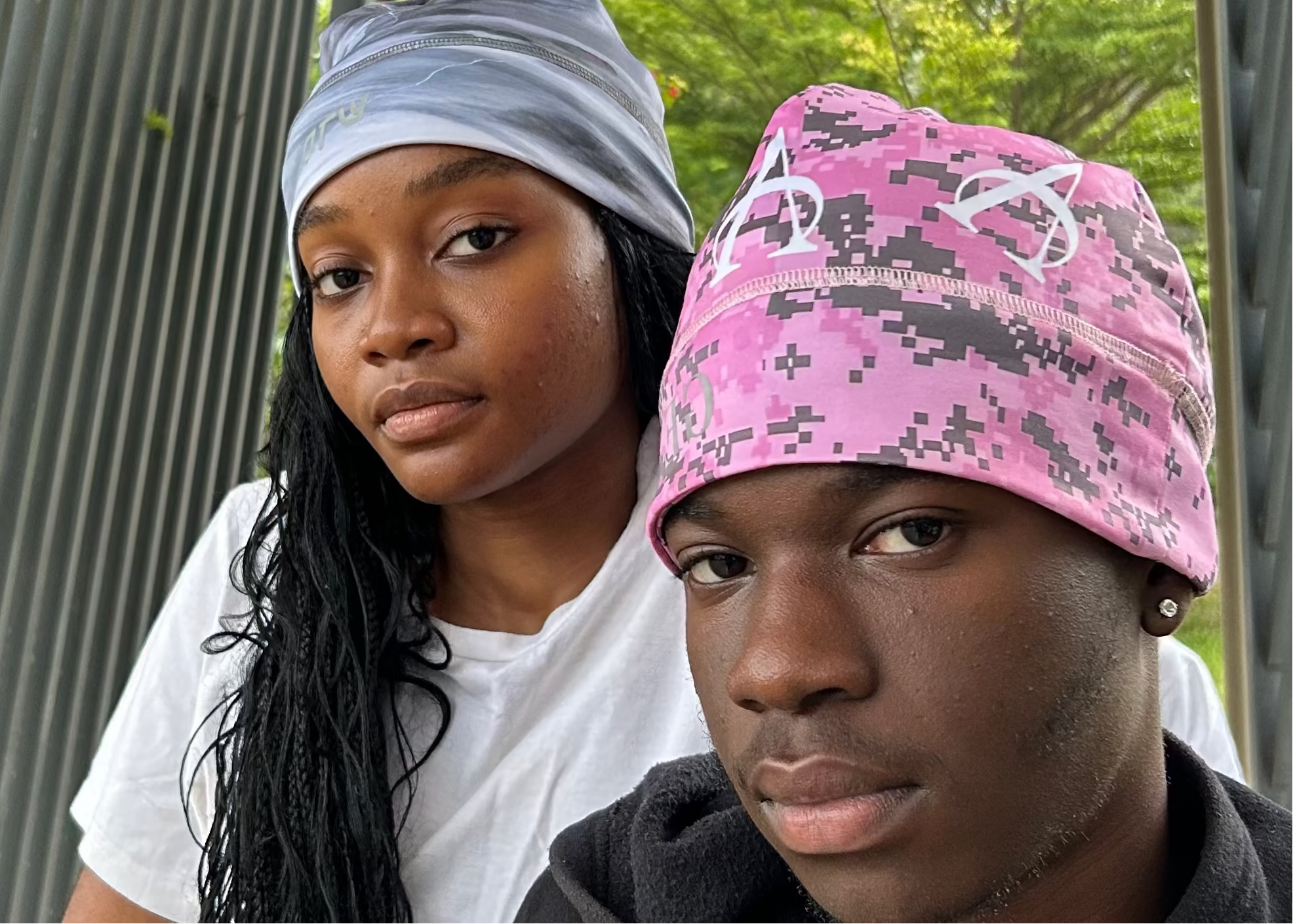 Two people wearing colorful headscarves standing outdoors with a natural background.